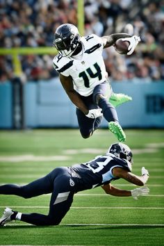 a football player is diving to catch the ball while another catches it with his hand