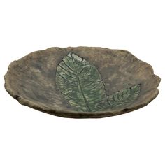 a leaf shaped bowl with green leaves on it