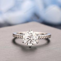 a white gold engagement ring with an old - fashioned twist band and a round diamond center