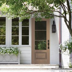 a white house with two planters on the front steps and a door in the back