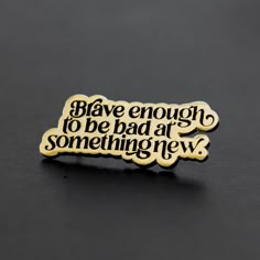 a black and gold pin with the words, have enough to be bad at something new