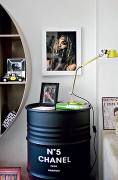 there is a black barrel in the corner next to a shelf with pictures on it