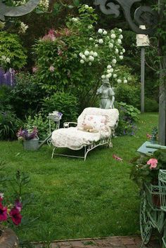 a chair and table in the middle of a garden with lots of flowers on it