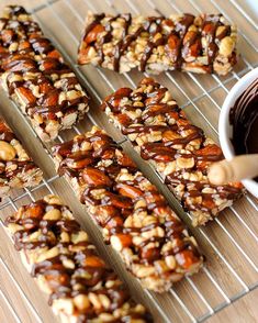 chocolate and nuts are arranged on a cooling rack next to a bowl of dipping sauce