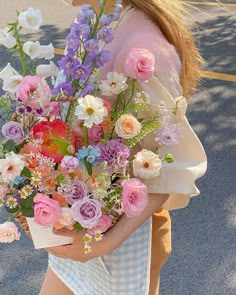 a woman is walking down the street holding a bouquet of flowers in her hands,