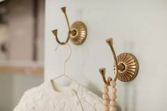 two brass sconces hang on the wall next to a white dress hanging from it's hooks