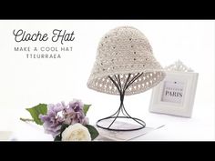 a white hat sitting on top of a table next to flowers