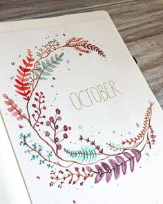 an open notebook with the word october written in gold on it and watercolor flowers