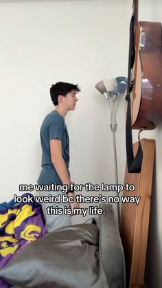 a young man standing in front of a tv next to a wall with a guitar on it