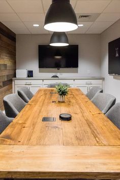 an empty conference room with wooden table and gray chairs in front of a projector screen