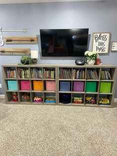 a tv mounted on the wall above a bookshelf filled with children's toys