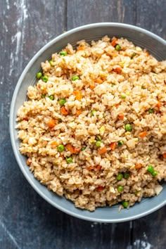 a bowl filled with rice and vegetables on top of a wooden table