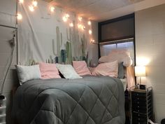 a bed with pink pillows and blankets in a room decorated with cactus wall hangings