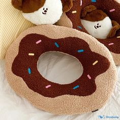 two stuffed animals are sitting next to a donut pillow