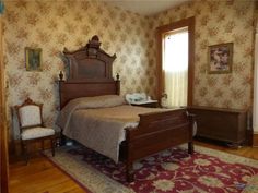 a bed room with a neatly made bed next to a chair and a rug on the floor