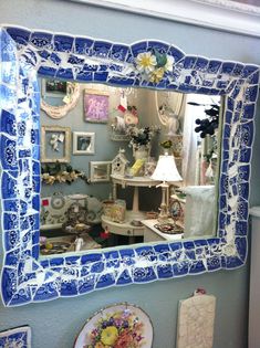 a blue and white mirror sitting on the side of a wall next to a toilet