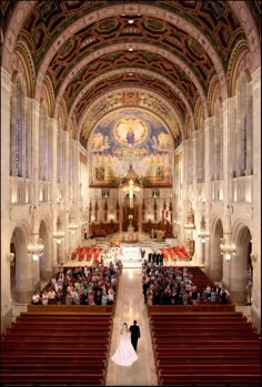 a bride and groom walking down the aisle of a large church with pews on both sides