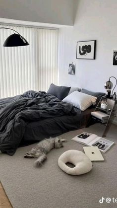 an unmade bed sitting on top of a floor next to a window with blinds