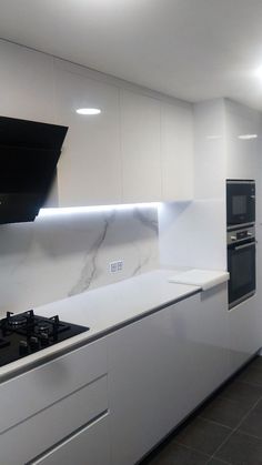 an empty kitchen with white cabinets and marble counter tops, along with black stove top ovens