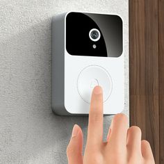 a person pressing the button on a smart home security system with their finger and thumb