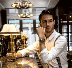 a man sitting at a bar with his hand on his chin and looking off to the side