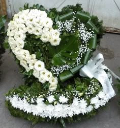 a wreath with white flowers and greenery on the ground next to a building door