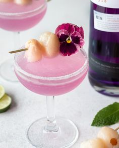 two glasses filled with pink cocktails and garnished with flowers