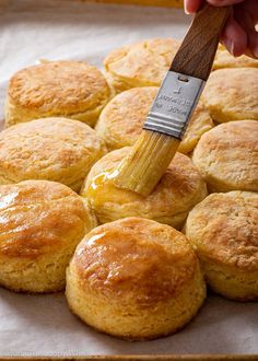 a person holding a brush over some biscuits