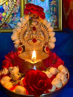 a golden plate with flowers and a lit candle in front of paintings on the wall