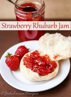 strawberry rhubarb jam is sitting on a plate next to some bread and strawberries