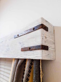 a wooden shelf with two hooks on it and some towels hanging from the wall next to it