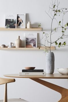 a table with some books and vases on it next to two shelves filled with pictures