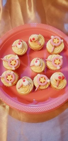 cupcakes are arranged on a pink plate with white frosting and stars in the middle