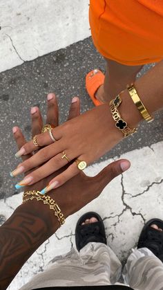 two people holding their hands together with different bracelets on each hand and one wearing an orange shirt