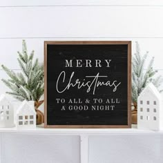 a black and white christmas sign sitting on top of a shelf next to small houses