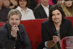 two men sitting next to each other in front of a crowd with microphones on