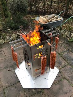 a grill with hot dogs hanging from it's sides and fire in the middle