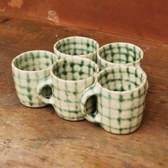 four green and white cups sitting on top of a wooden table