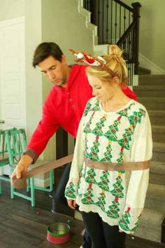 a man and woman standing next to each other in front of a stair case with christmas decorations on it