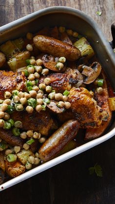 a casserole dish with chicken, beans and vegetables in it on a wooden table