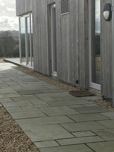 an outside view of a wooden building with glass doors and gravel path leading up to it