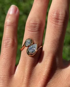 a woman's hand with a ring on it that has two pear shaped diamonds