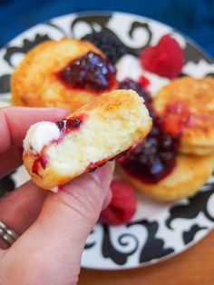 a hand holding a pastry with berries and cream on it