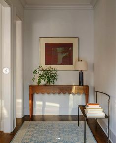 a living room with a rug, table and plant on the floor in front of it