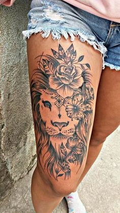 a woman's thigh with a lion and flowers tattoo on the side of her leg