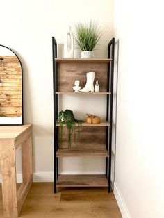 a wooden shelf with some plants on top of it next to a table and mirror