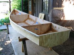 a wooden boat sitting on top of a piece of plywood next to a building