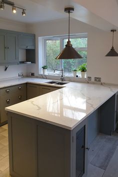 a large kitchen with an island in front of the sink and stove top, along with two pendant lights