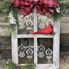 a red bird sitting on top of a window sill decorated with evergreen branches and ornaments