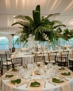 the table is set with white linens and greenery